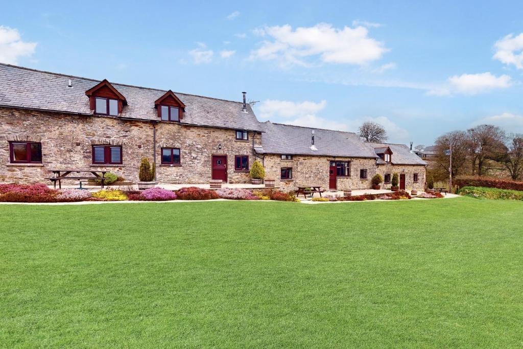 a large stone house with a green lawn at West Hollowcombe Farm Cottages - full site in Dulverton