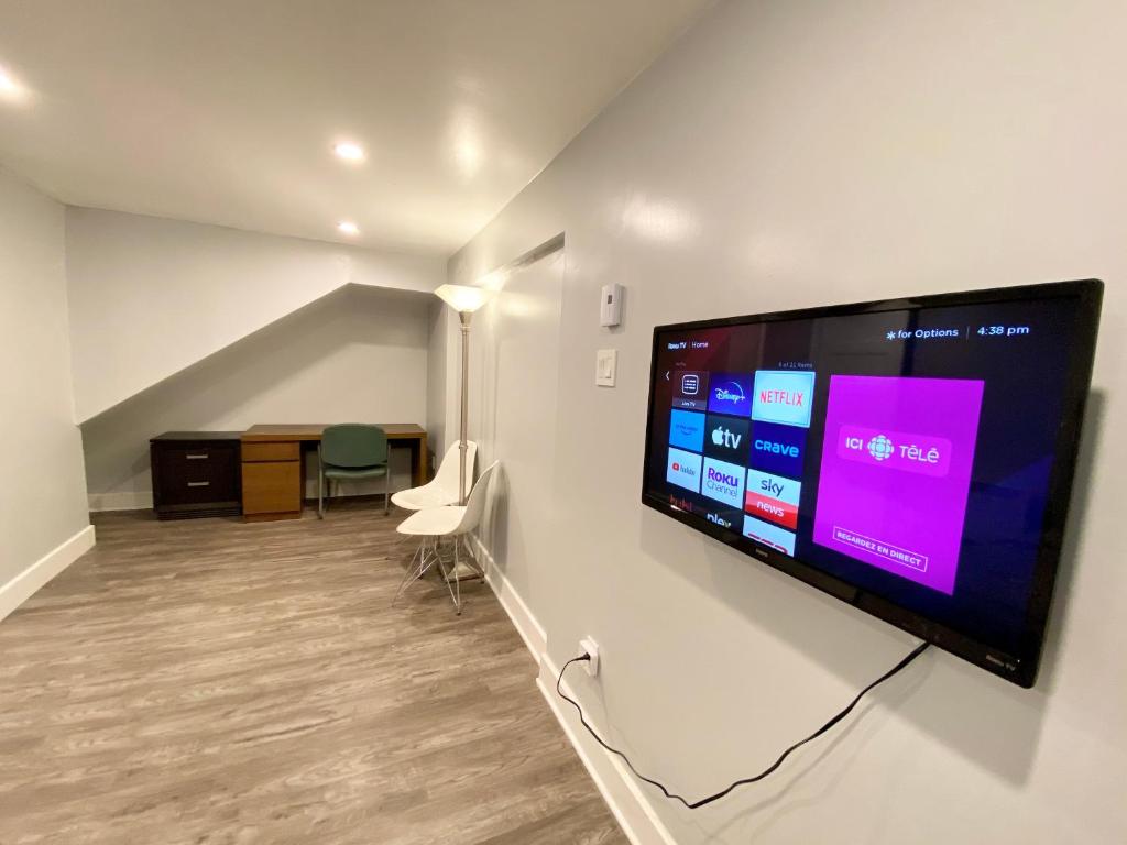 a room with a large flat screen tv on a wall at MontREAL HOMES - Affordable Rooms, Smart TV, Shared Kitchen in Montréal