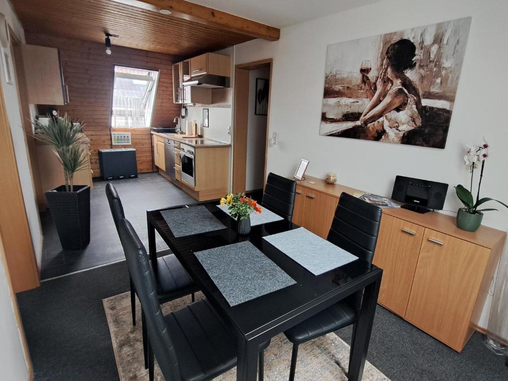 Friolzheim的住宿－Cosy Retreat in Friolzheim，厨房以及带黑色桌椅的用餐室。