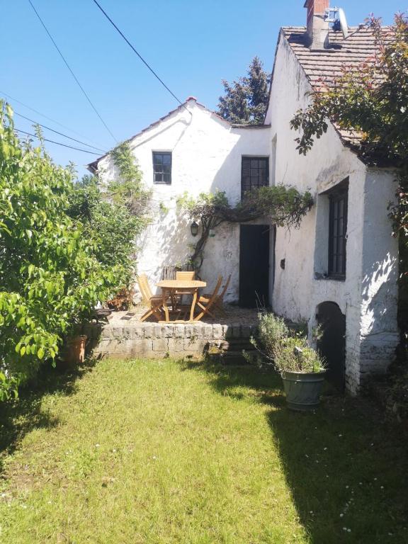 une petite maison blanche avec une table dans la cour dans l'établissement Le cottage à 40 min de Paris, à Luzarches