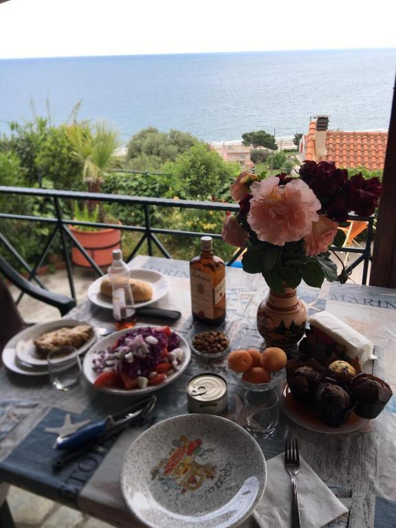 una mesa con platos de comida y un jarrón de flores en Villa Velika GR, en Velika