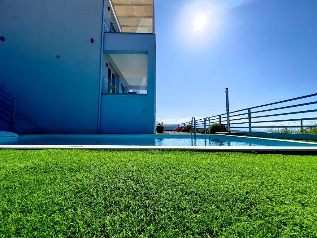una piscina con prato verde accanto a un edificio di Sun Angelo luxury apartment in Paradise 1 ad Arménoi