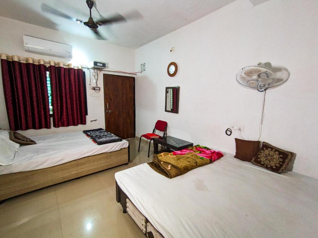 a room with two beds and a chair in it at Jay Kuber Home stays in Garudeshwar