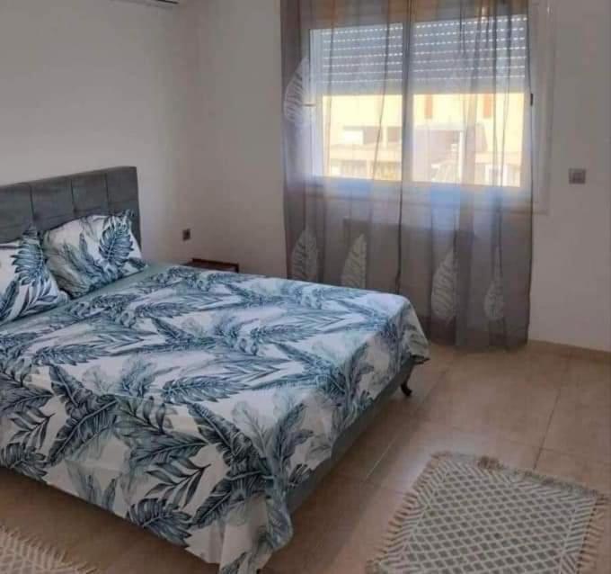 een slaapkamer met een bed met een blauwe en witte deken bij إقامة طلال in El Ahmar