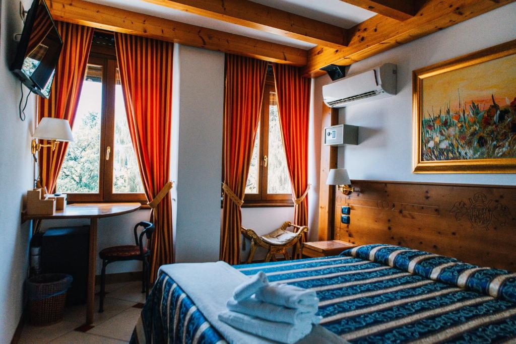 a bedroom with a bed and a desk and windows at Arciduca Charming House Room & Breakfast in Arco