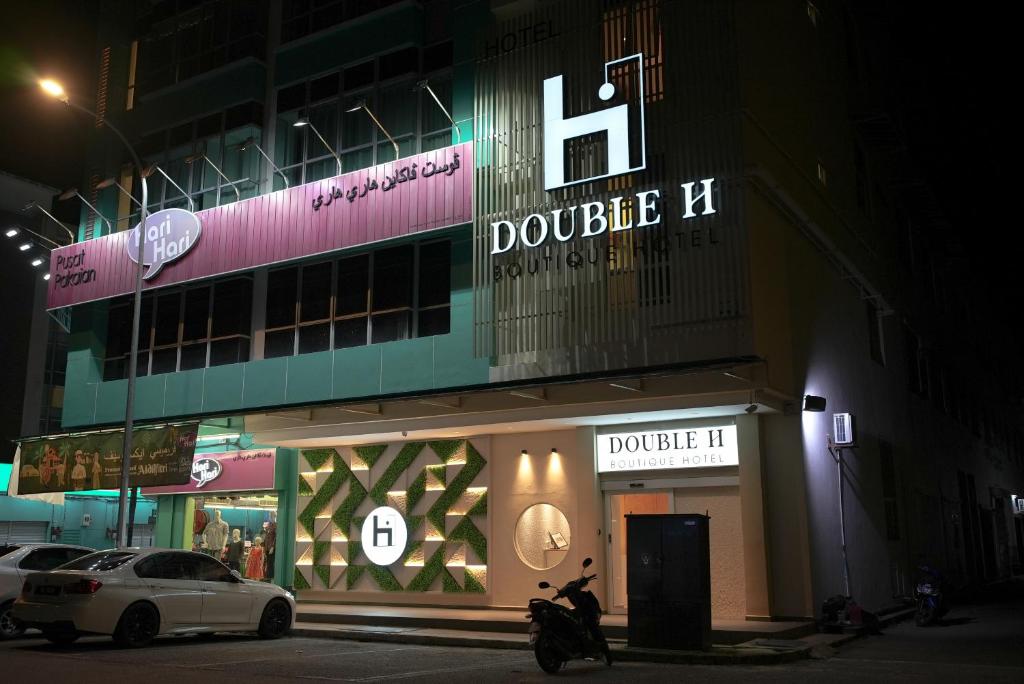 瓜拉丁加奴的住宿－Double H Boutique Hotel，停在前面的一座带摩托车的建筑