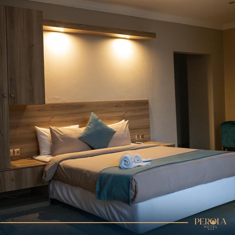 1 dormitorio con 1 cama grande y cabecero de madera en PEROLA HOTEl en Maputo