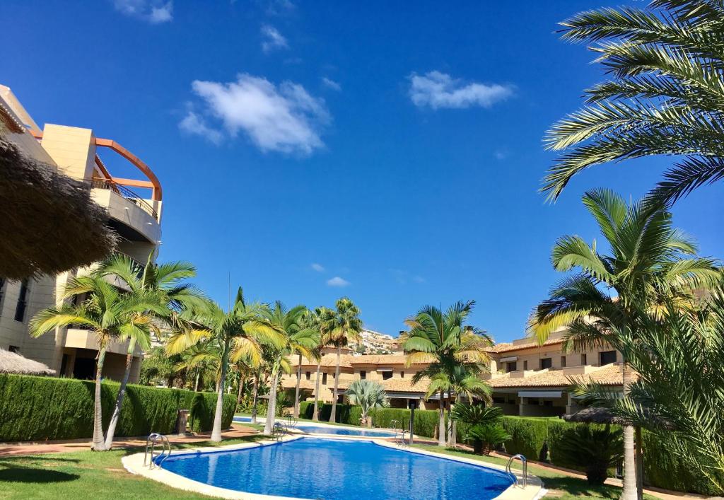 a pool with palm trees in front of a building at Luxury spa living in Jávea
