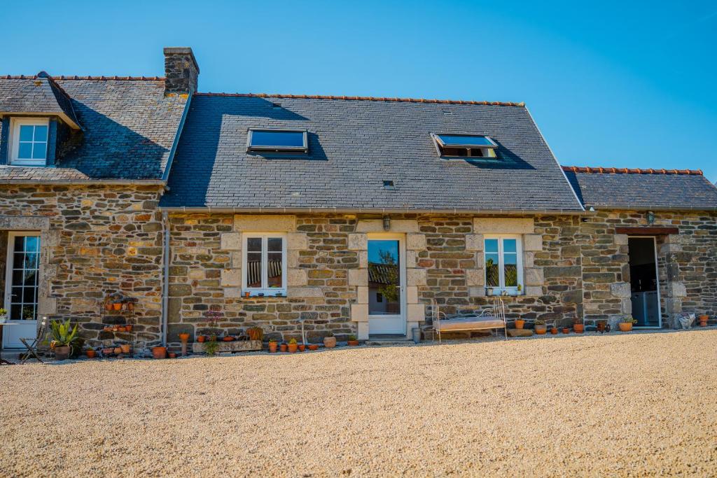une vieille maison en pierre avec des fenêtres bleues et une cour dans l'établissement les gîtes de Blandines II, à Peumérit