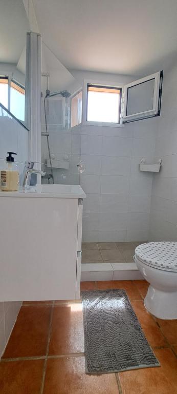 a white bathroom with a shower and a toilet at Casa Leon Fuerteventura in Corralejo