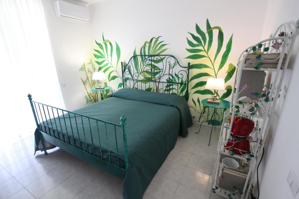 a bedroom with a green bed and plants on the wall at Jungle Rooms in Cetara