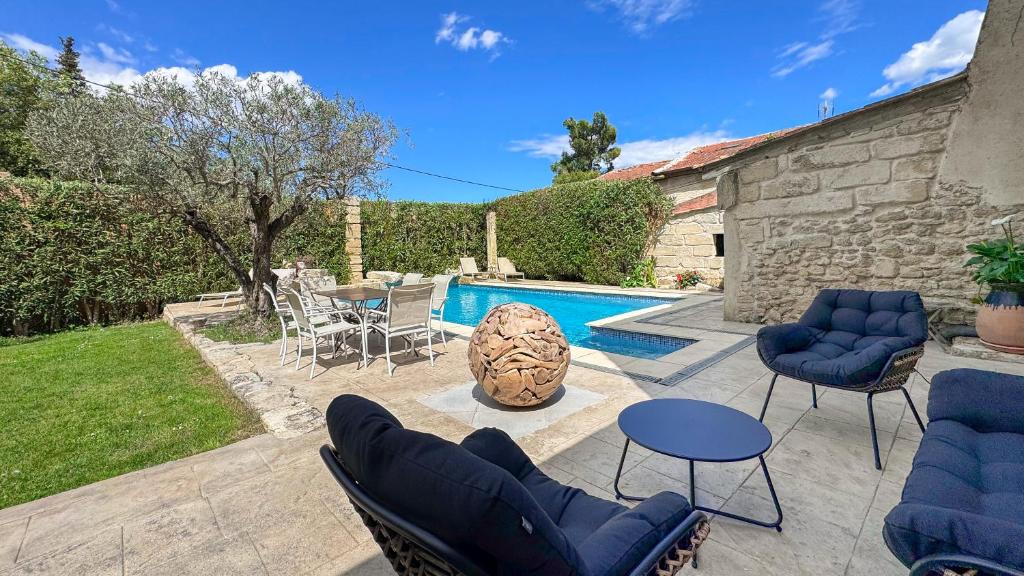 um pátio com cadeiras, uma mesa e uma piscina em Très beau mas provençal proche Alpilles em Barbentane