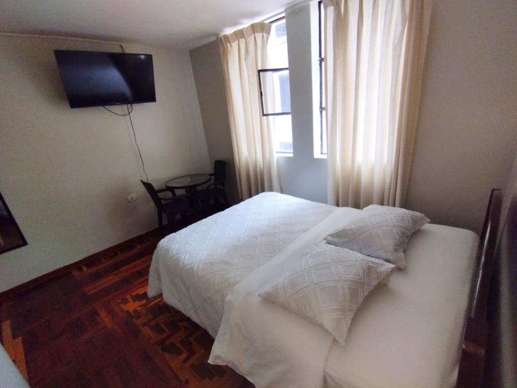 a bedroom with a white bed and a window at Hotel la encantada in Cajamarca