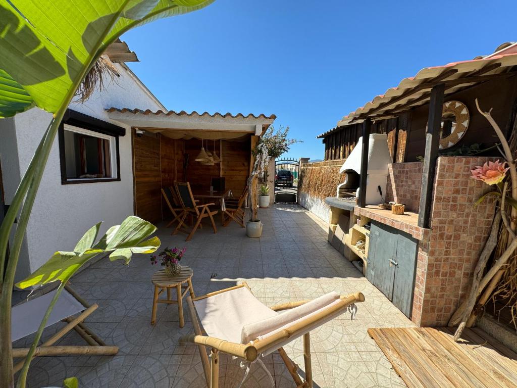 un patio avec une table, des chaises et un barbecue dans l'établissement Casita Louise Maison de plage bohème, à Lucciana