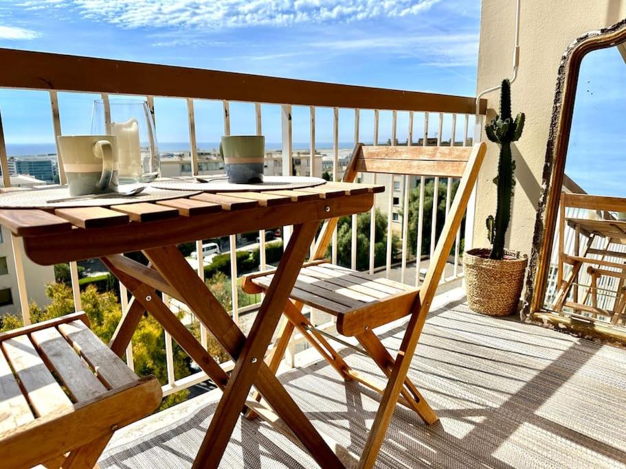 una mesa de madera y una silla en el balcón en Joli 2 pièces - Proche aéroport - Terrasse vue mer, en Niza