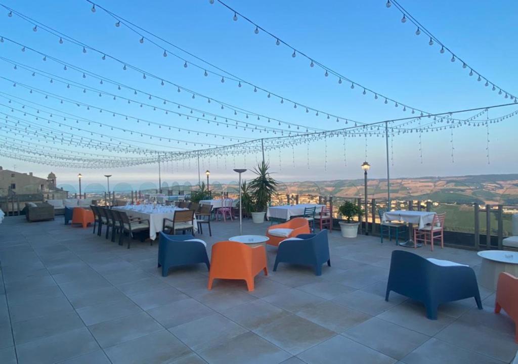 een dakterras met tafels, stoelen en verlichting bij Hotel Astoria in Fermo