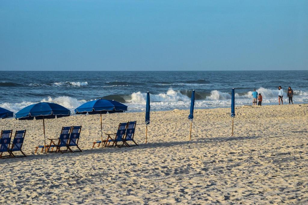 - un groupe de chaises longues et de parasols sur une plage dans l'établissement Beautiful 3 Bedroom BEACHFRONT Condo (F3) - Sleeps 10, à Gulf Shores