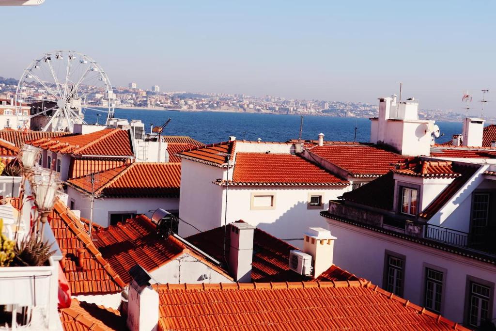 a view of roofs of buildings and a ferris wheel at Sea View Wterrace 2 Mins From Beach In Old Town in Cascais