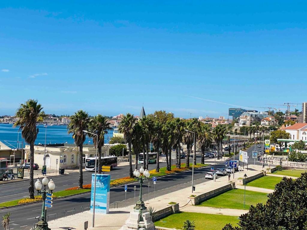 una strada cittadina con palme e una strada con macchine di Sea View 2 Mins Walk To Beach And Estoril Casino a Estoril
