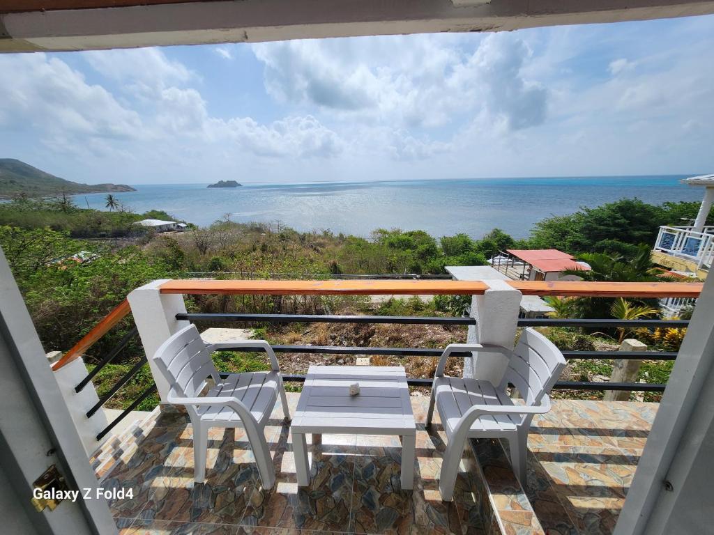 balcón con mesa, sillas y vistas al océano en Sea Breeze inn 101, en Providencia
