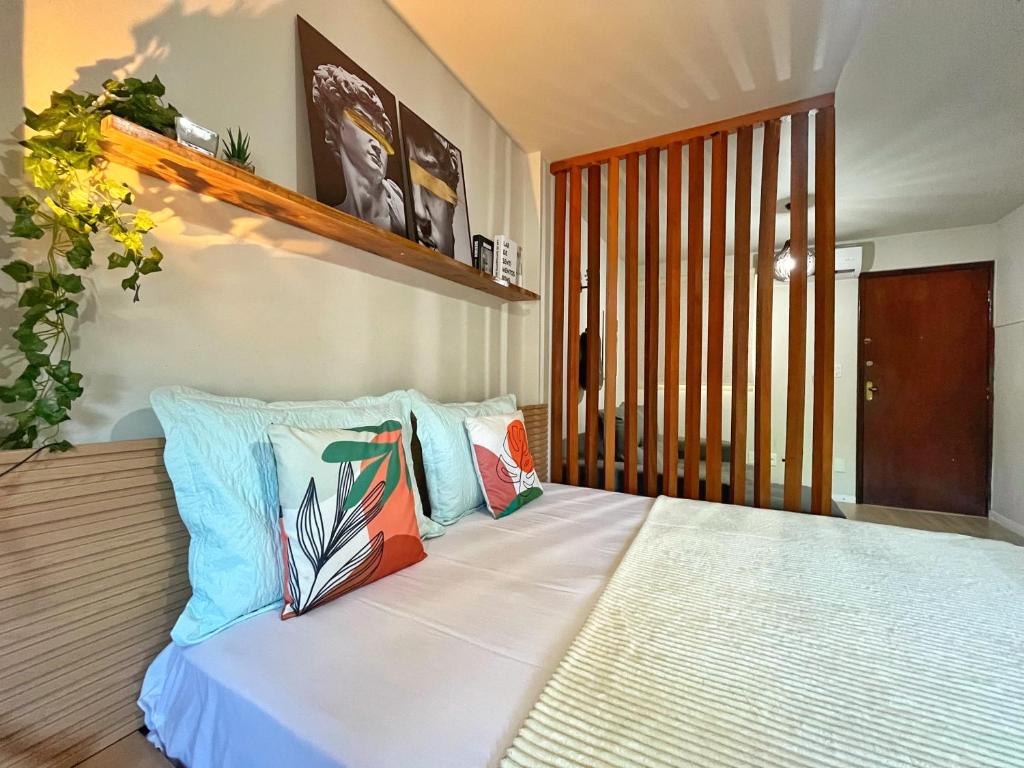 a bedroom with a bed with colorful pillows at LOFT aconchegante no Centro de Macaé, Wifi, Ar condicionado e Cozinha completa in Macaé