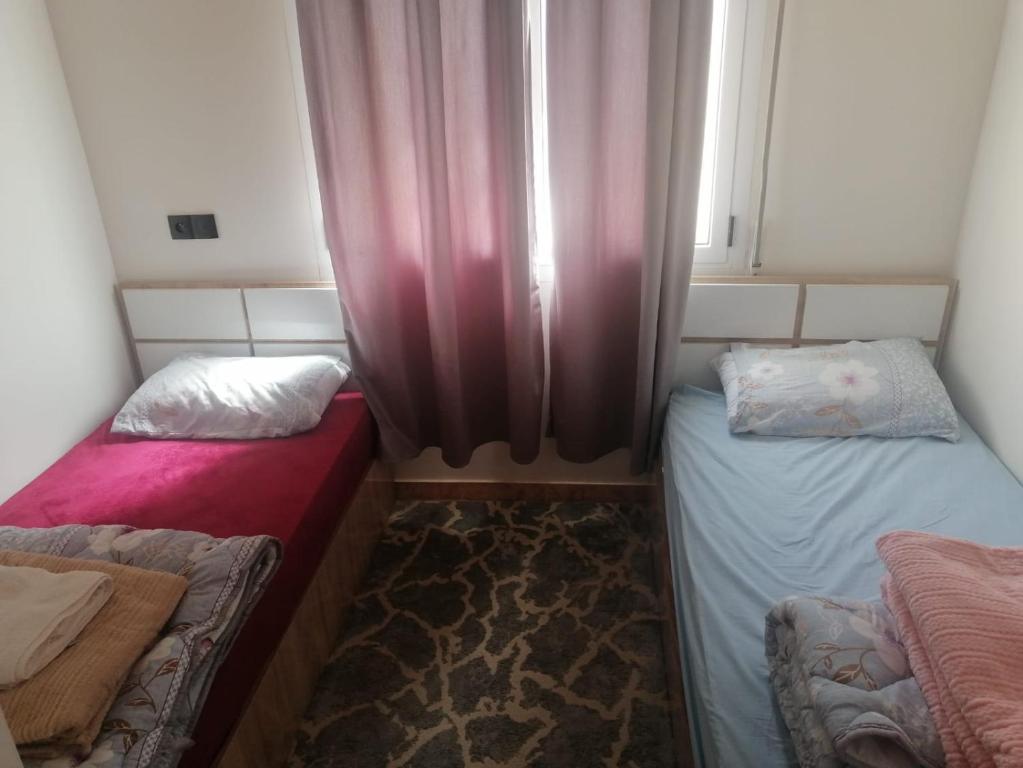 a small room with two beds and a window at Airport apartment 2 