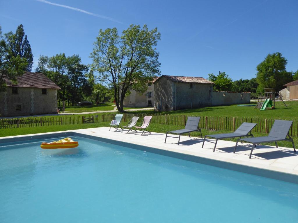 einer Gruppe von Stühlen und einem Pool mit einem Floß in der Unterkunft Domaine La Moulinasse in Chassaignes