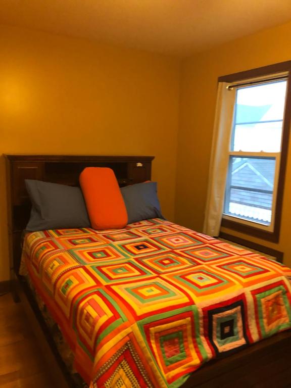 Un dormitorio con una cama con una almohada naranja y una ventana en Room to stay in, en South Ozone Park