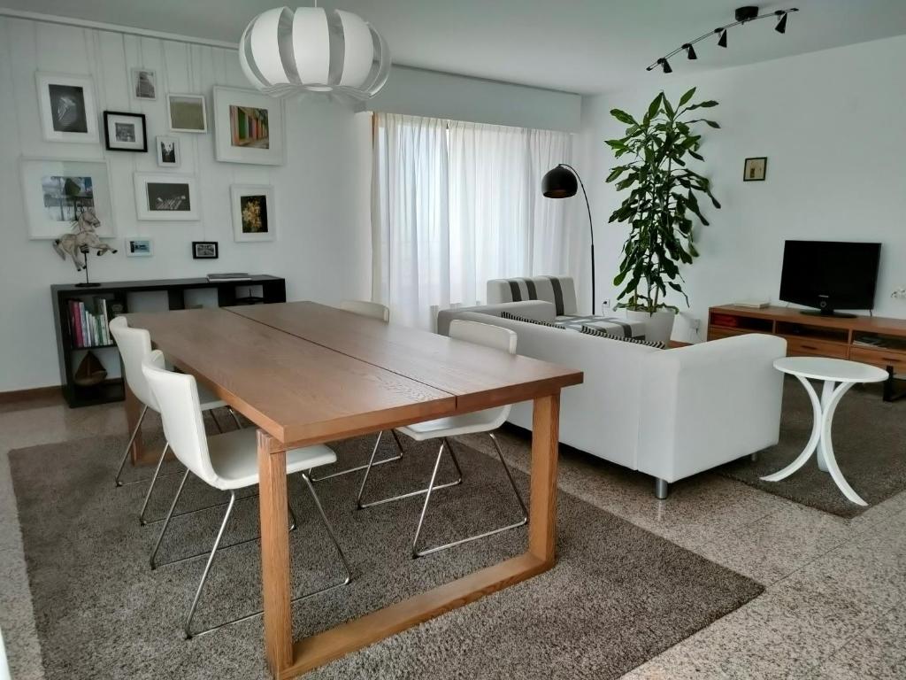 a living room with a wooden table and white chairs at Douro View Apartment in Vila Nova de Gaia
