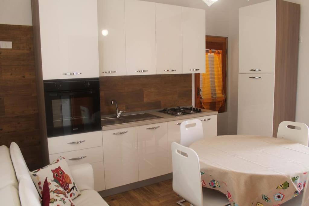 a kitchen with white cabinets and a table and a sink at Casetta Girasole a due passi dal mare in Capilungo