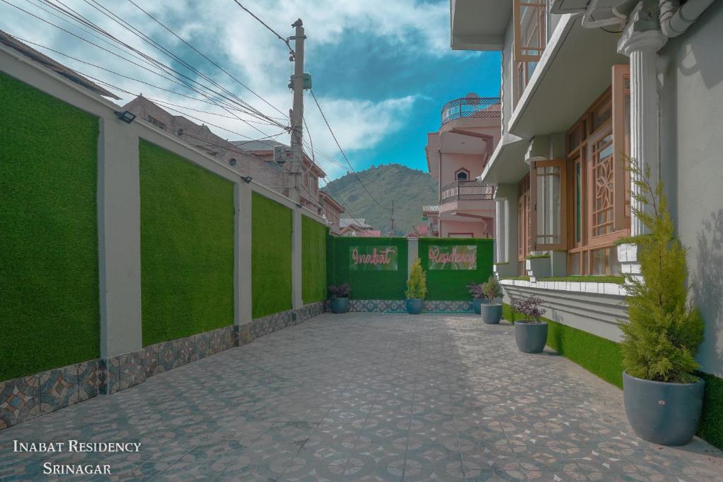 a walkway between two buildings with green walls at Hotel Inabat Residency in Srinagar