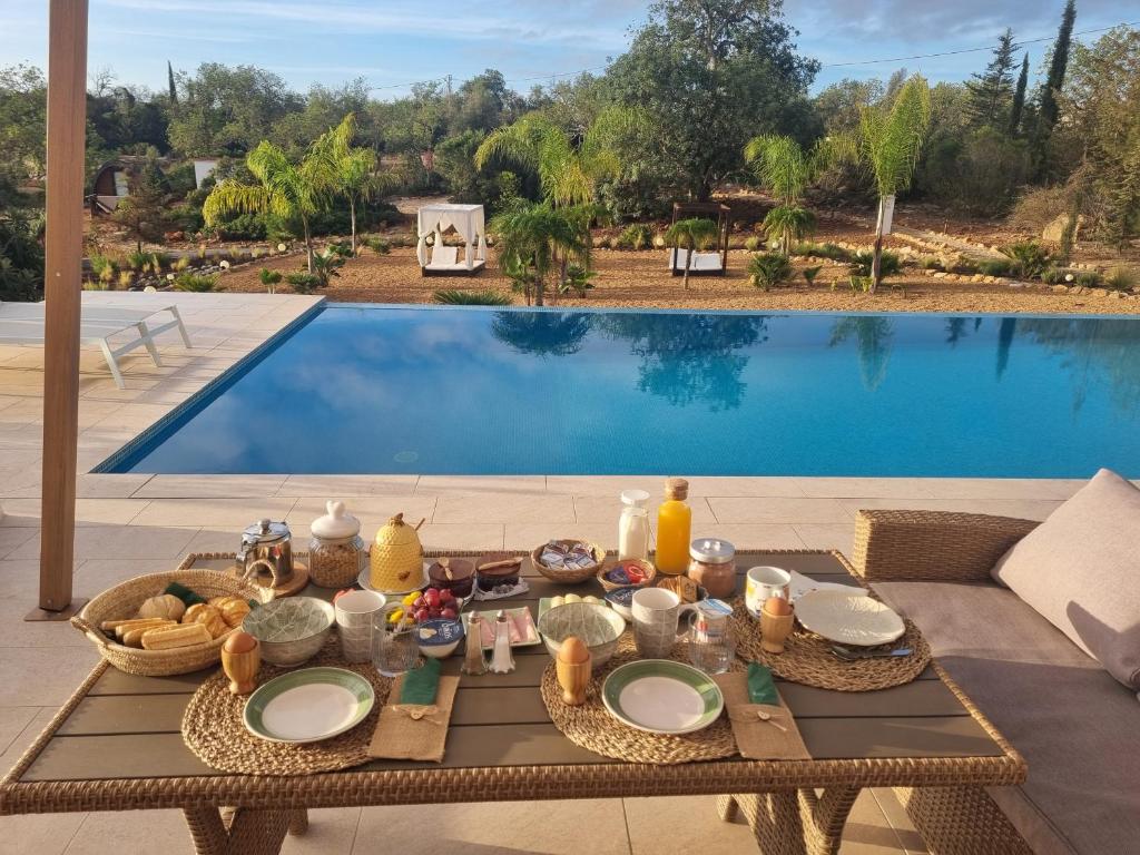 uma mesa com comida ao lado de uma piscina em Eco Cabin - Villa das Alfarrobas em Algoz