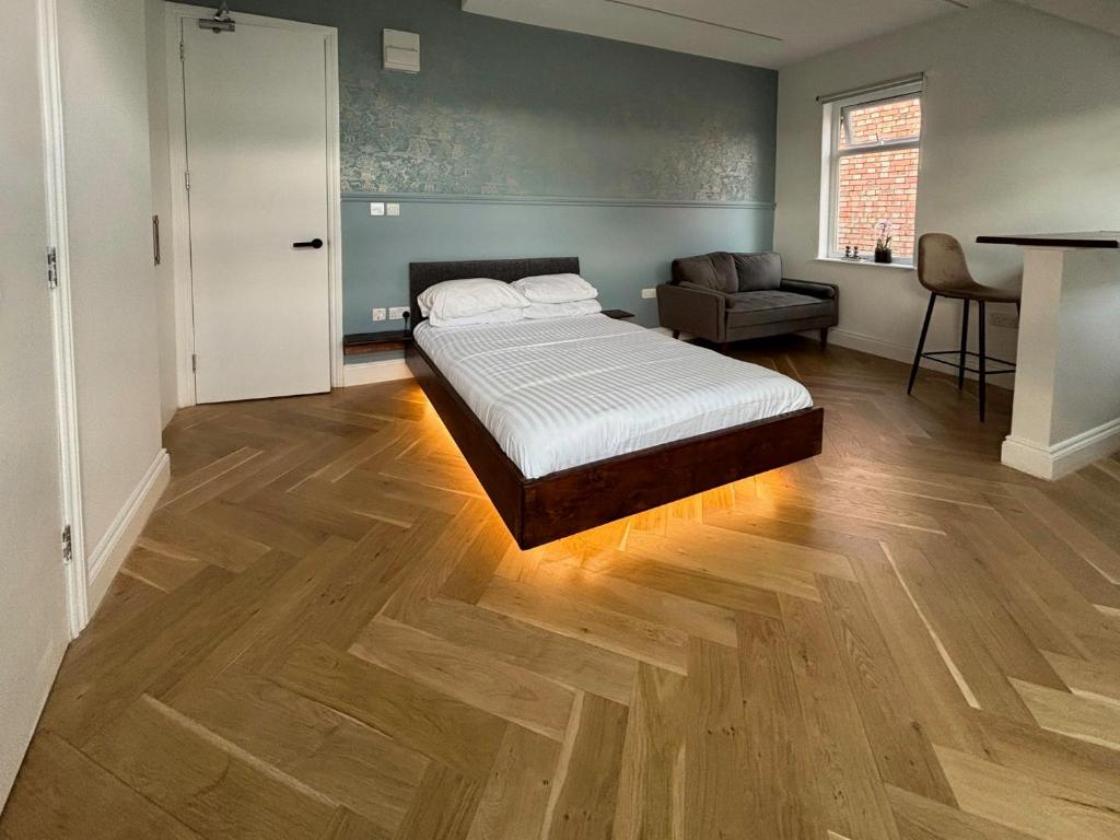1 dormitorio con 1 cama y 1 silla en una habitación en London Studios and Suites, en Harrow