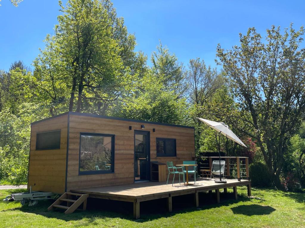a tiny house with a deck and a table at Moho Nat’ure Tiny-house in Saint-Nabord