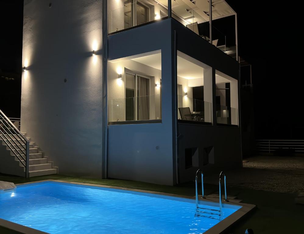 a swimming pool in front of a house at night at Sun Angelo luxury apartment in Paradise 1 in Arménoi