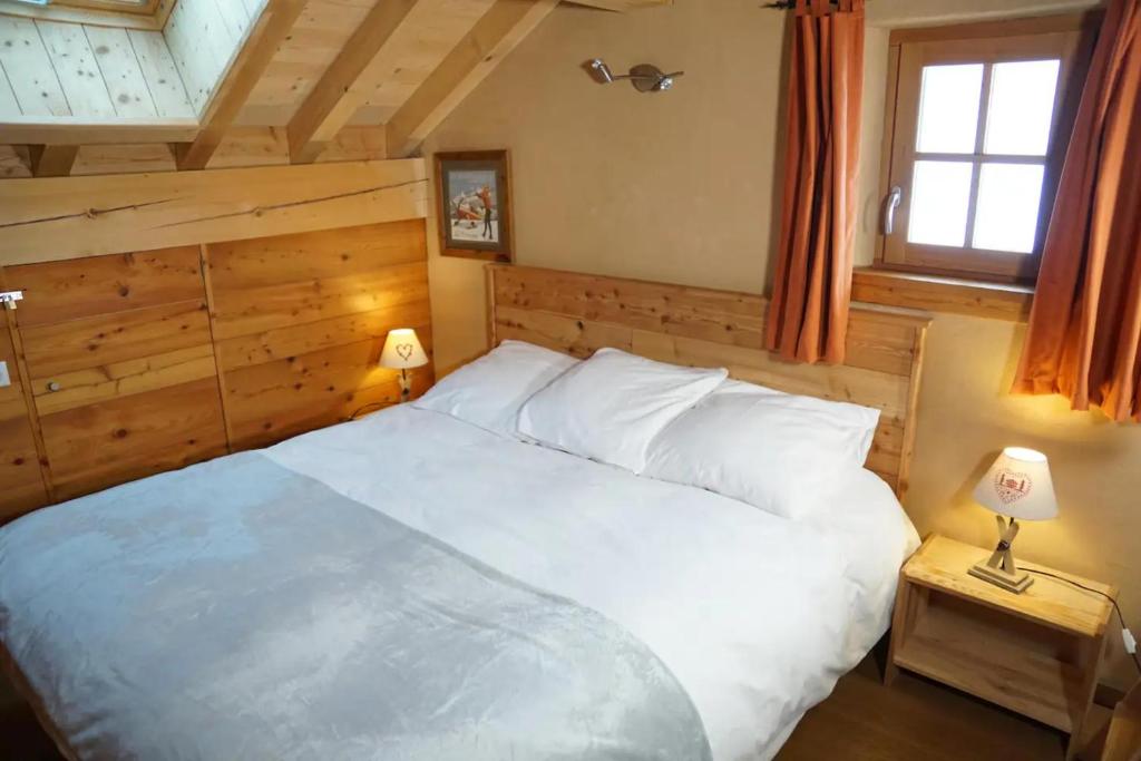 1 dormitorio con 1 cama blanca grande y 2 lámparas en Chalet Les Ecrins, en Villard-Reculas