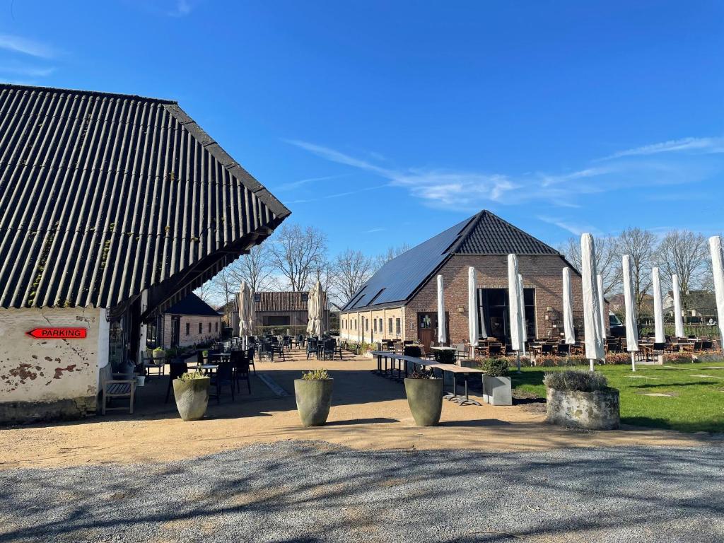 a building with a black roof and tables and chairs at Bouwelhoeve 't Schuur in Grobbendonk