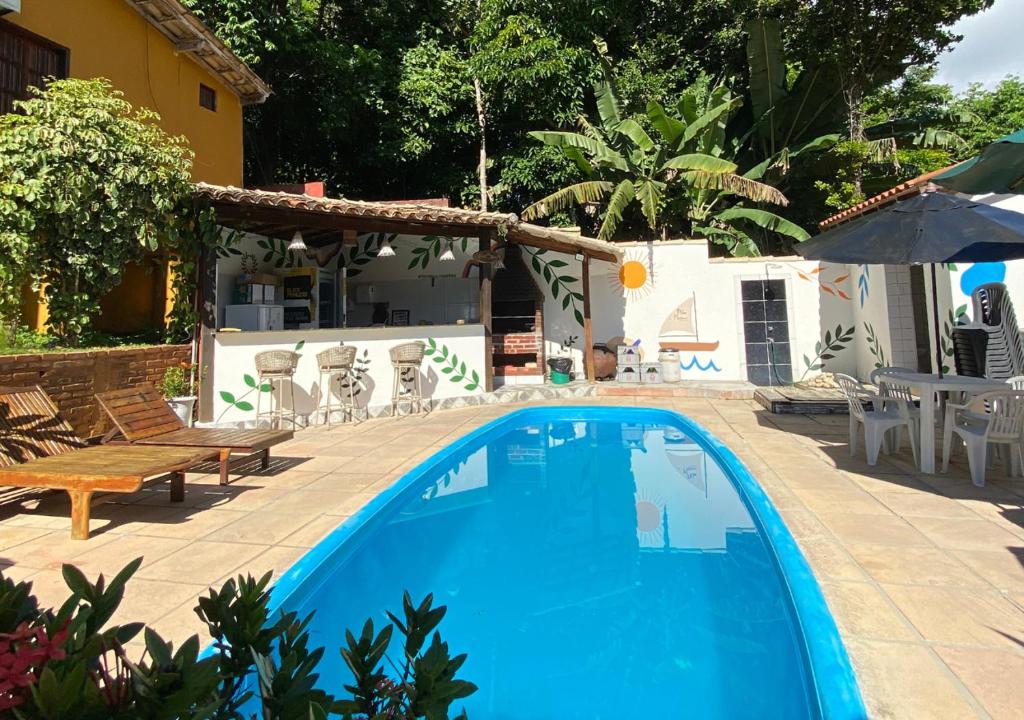 a blue swimming pool in a yard with a house at Pousada Alto da Praia in Arraial d'Ajuda