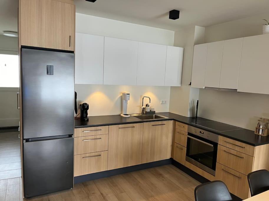eine Küche mit weißen Schränken und einem Kühlschrank aus Edelstahl in der Unterkunft Two bedroom family apartment in Akureyri