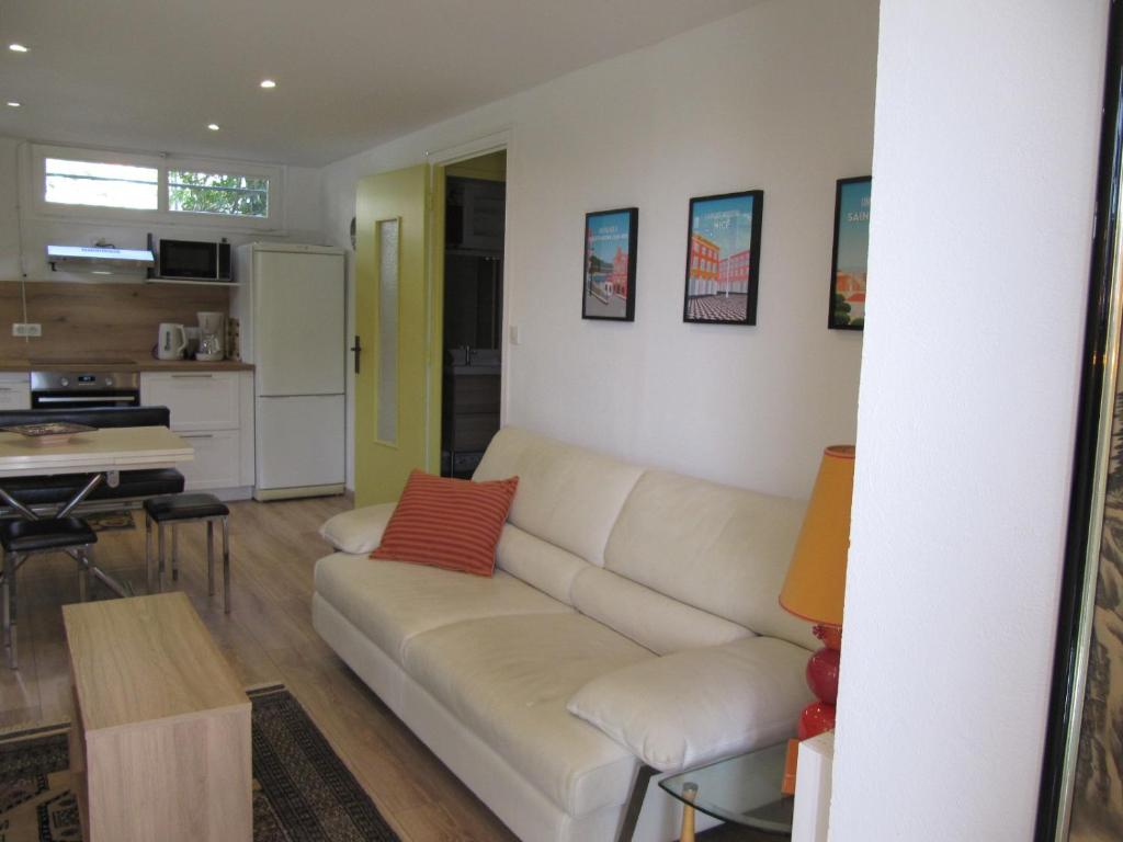 un salon avec un canapé blanc et une cuisine dans l'établissement Sur les hauteurs de VENCE, à Vence