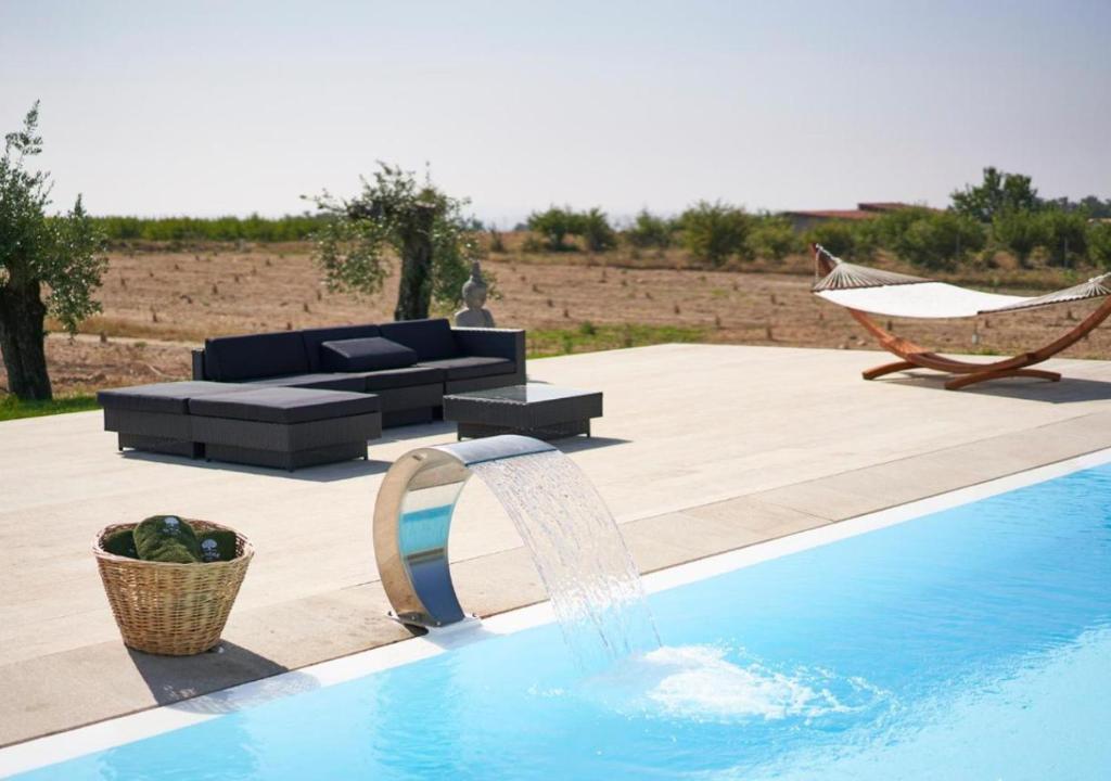 una piscina con una fuente y una hamaca en Oliveira House - Deluxe Bedrooms, en Castelo Novo