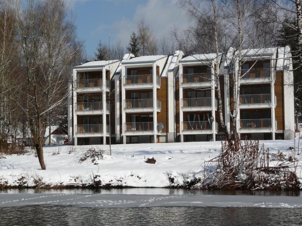an apartment building in the snow next to a river at Apartamenty Wiślany Brzeg in Ustroń