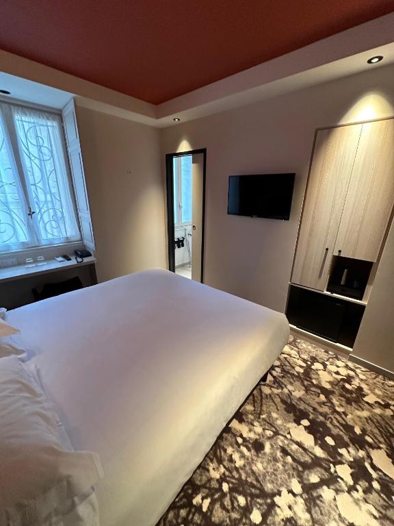 a bedroom with a large white bed and a television at Hôtel Le Médiéval Palais des Papes in Avignon
