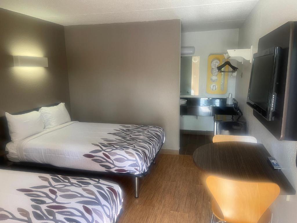 Habitación de hotel con cama, escritorio y TV. en PT 6 INN en Evansville