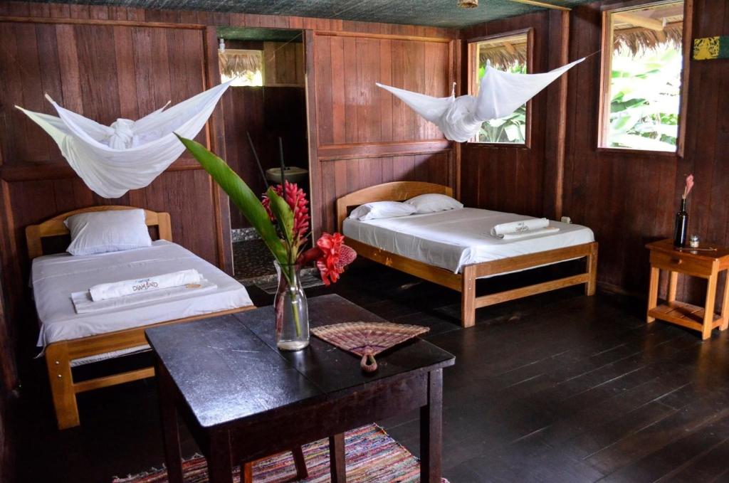 ein Schlafzimmer mit 2 Betten und einem Tisch mit Blumen darauf in der Unterkunft River Point Hostel in Puerto Maldonado