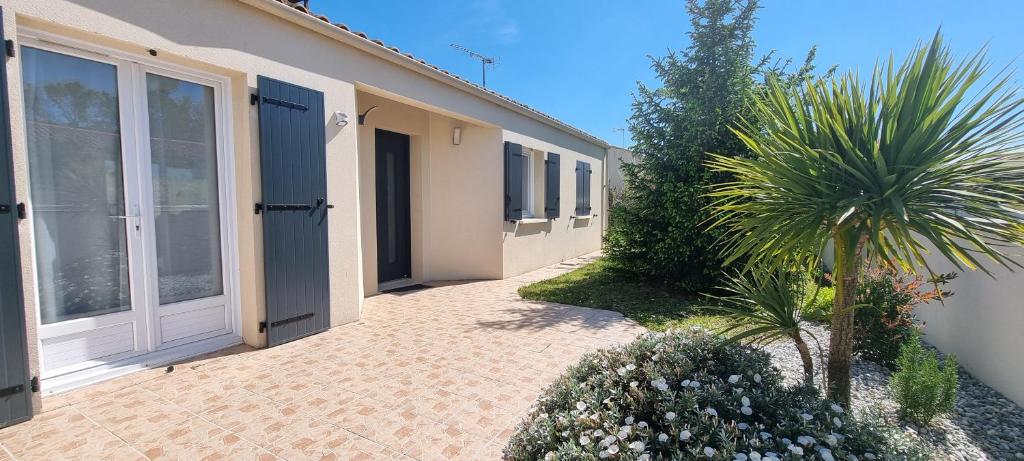 un edificio con una puerta y una palmera al lado en HOUSE CLOSE TO ROYAN AND SEASIDE, GROUND FLOOR, QUIET AND COMFORTABLE en Médis