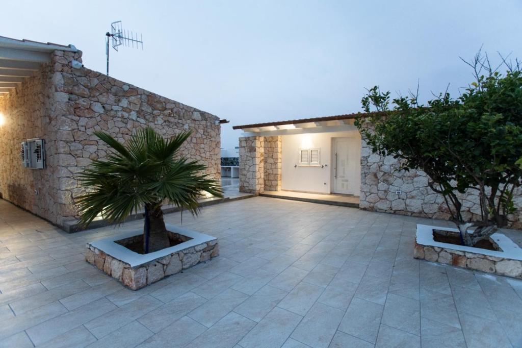 a courtyard with two potted trees and a building at Villa Angel Lampedusa. in Lampedusa