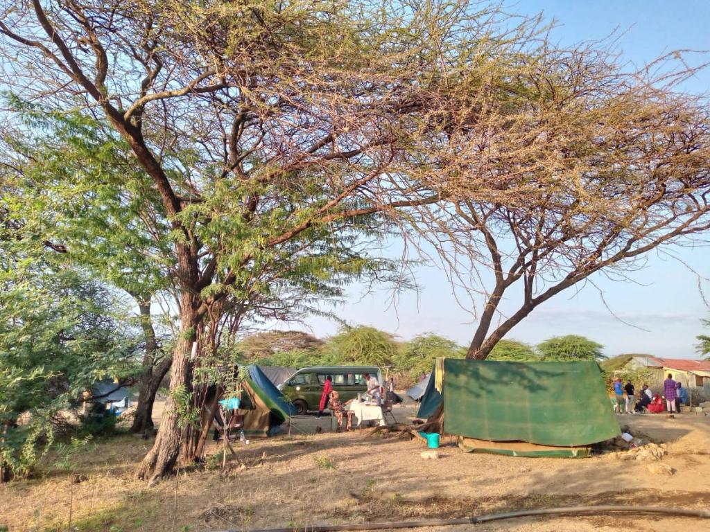 a group of people sitting under trees and tents at Popo Camp Lake Baringo in Ol Kokwe
