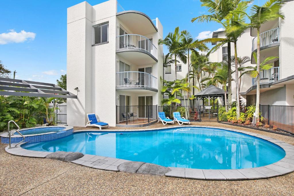 a swimming pool with a large white building at Beachside Mooloolaba in Mooloolaba