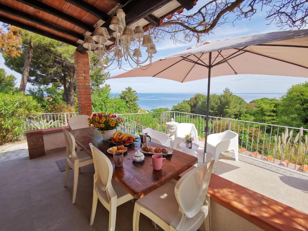 uma mesa e cadeiras num pátio com um guarda-sol em casa panoramica bouganville em SantʼAndrea